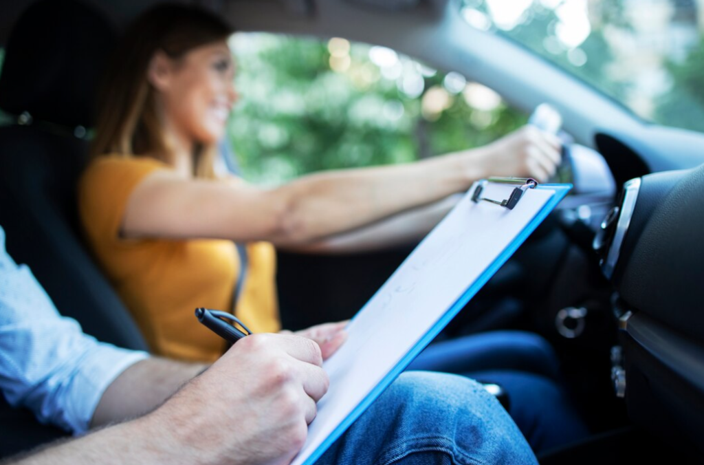 Donna al volante sorride mentre un istruttore annota su un foglio